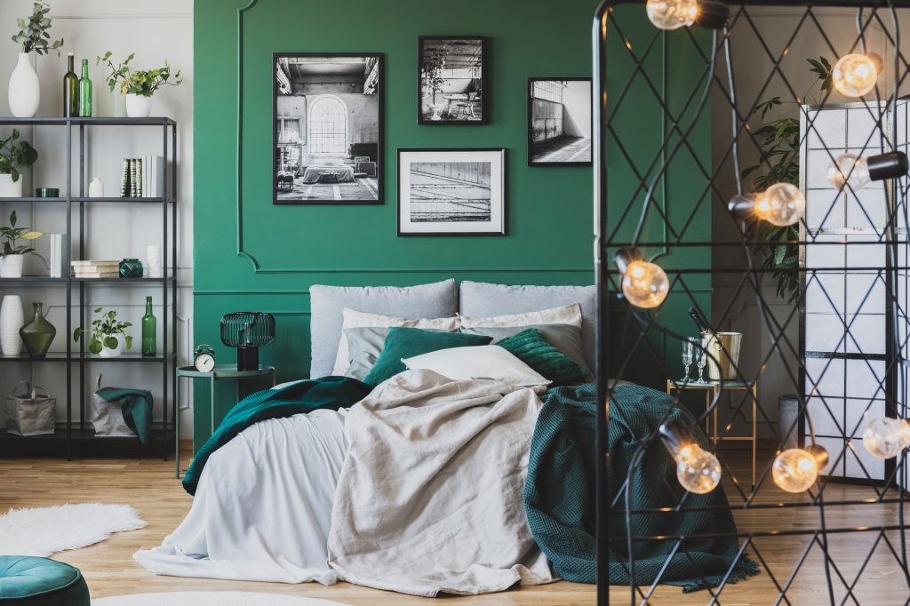 Cozy bed with pillows and blankets in emerald and grey colors